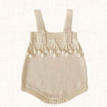 Cream knit romper with pom-pom trim and adjustable straps, front view